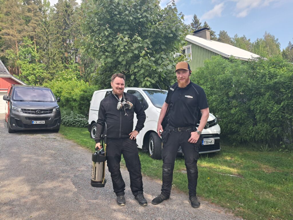Kaksi Tampest Oy:n tuholaistorjujaa valmiina työtehtäviin Tampereen seudulla. Taustalla huomaamattomia työautoja kotitalouskohteessa.